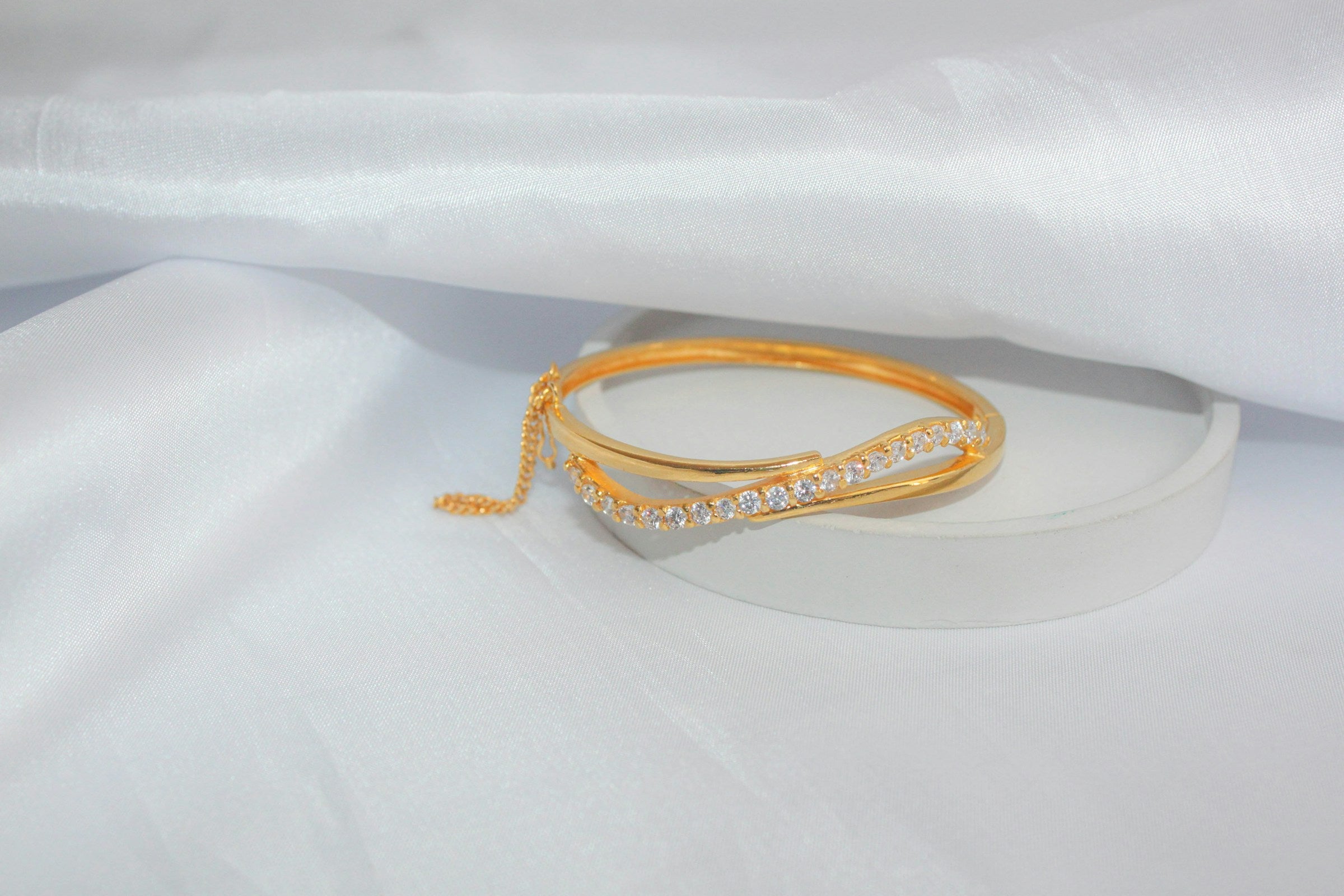 Close-up of a gold bracelet on soft neutral fabric